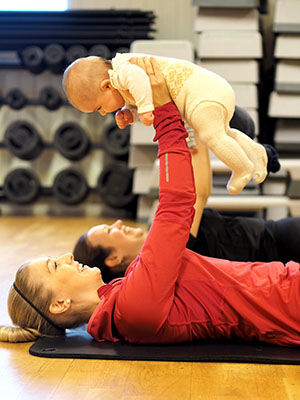 Bilde fra barseltrening hvor baby blir løftet opp mot taket